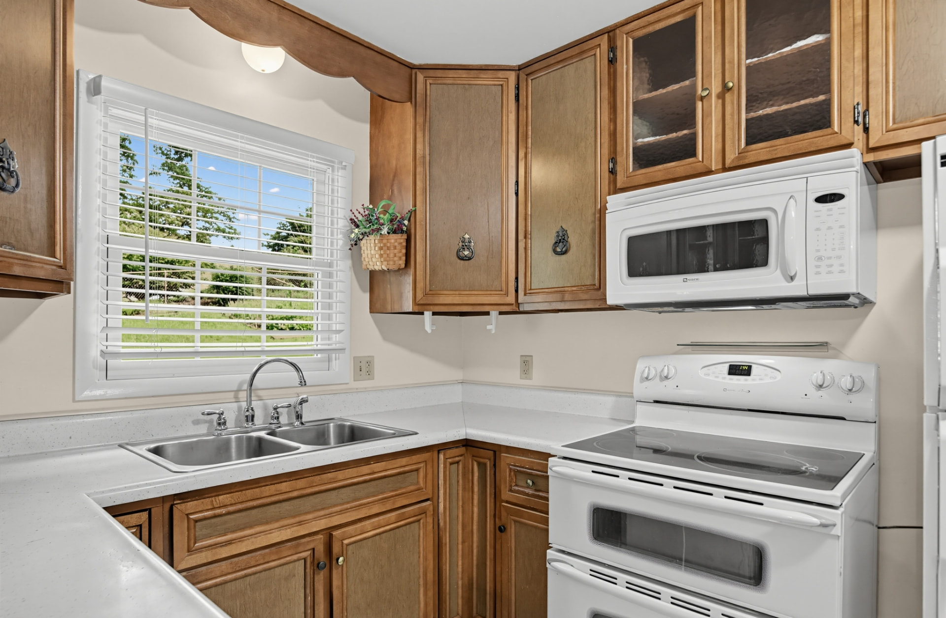 Kitchen with double sink, range, microwave and glass-front cabinets
