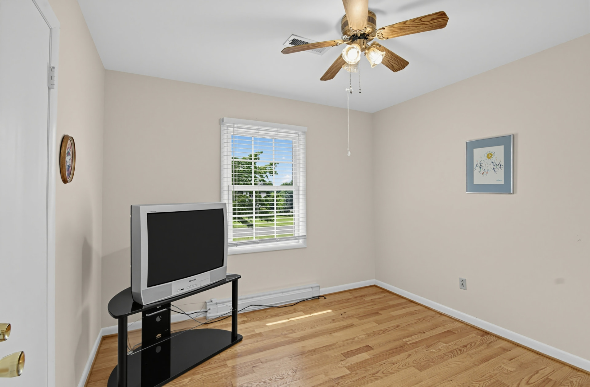 Bedroom with a sunny window, hardwood floors and ceiling fan