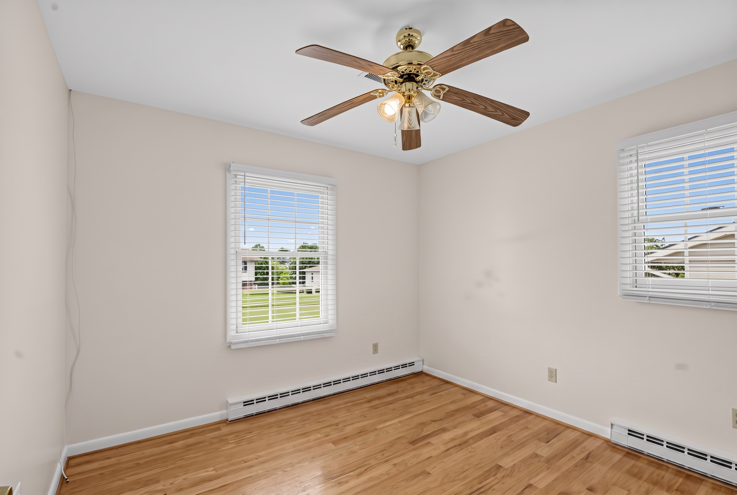 Corner bedroom with two windows, hardwood floors and ceiling fan